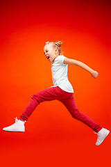 Image showing Young happy caucasian teen girl jumping in the air, isolated on red studio background.