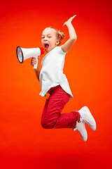 Image showing Beautiful young child teen girl jumping with megaphone isolated over red background