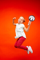 Image showing Beautiful young child teen girl jumping with megaphone isolated over red background