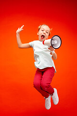 Image showing Beautiful young child teen girl jumping with megaphone isolated over red background