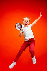 Image showing Beautiful young child teen girl jumping with megaphone isolated over red background