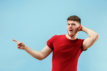 Image showing Young man with disgusted expression repulsing something, isolated on the blue
