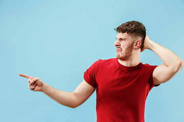 Image showing Young man with disgusted expression repulsing something, isolated on the blue