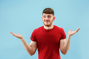 Image showing Beautiful male half-length portrait isolated on blue studio backgroud. The young emotional surprised man