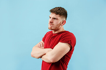 Image showing The young emotional sad angry man on blue studio background