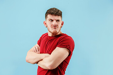 Image showing The young emotional sad angry man on blue studio background