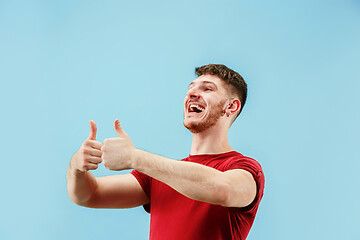 Image showing The happy businessman standing and smiling against blue background.