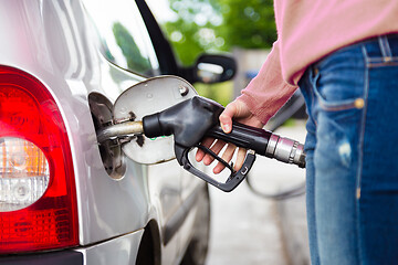 Image showing Lady pumping gasoline fuel in car at gas station.