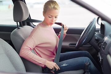 Image showing Beautiful woman fastening seat belt in small personal car.