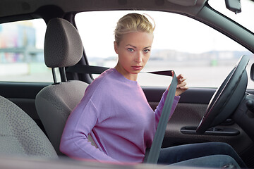 Image showing Beautiful woman fastening seat belt in small personal car.