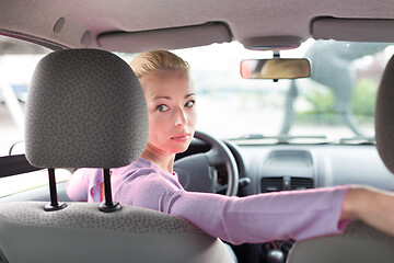 Image showing Female driver looking back while reversing in car.