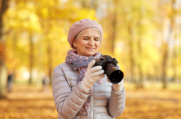 Image showing senior woman with photo camera at autumn park