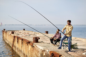 Image showing happy friends with fishing rods on pier