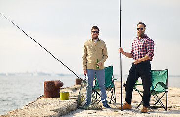 Image showing happy friends with fishing rods and beer on pier