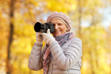 Image showing senior woman with photo camera at autumn park