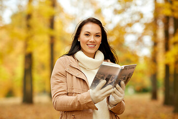 Image showing happy young woman with city guide in autumn park