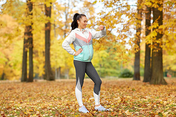 Image showing woman looking at fitness tracker in autumn park