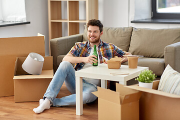 Image showing smiling man drinking beer and eating at new home