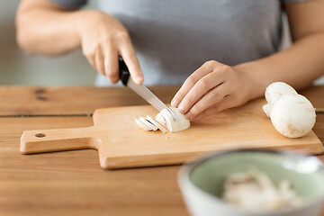 Image showing woman cutting champignons by knife on board