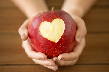 Image showing close up of hands holding apple with carved heart