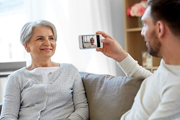 Image showing adult son photographing senior mother at home