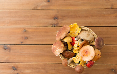 Image showing basket of different edible mushrooms on wood