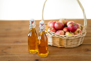 Image showing apples in basket and bottles of juice on table