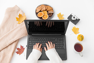 Image showing woman\'s hands typing laptop, tea and autumn leaves