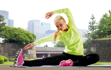 Image showing woman stretching on exercise mat at city park