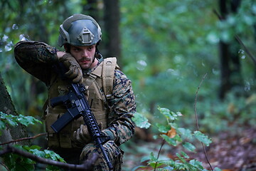 Image showing soldier preparing tactical and commpunication gear for action ba