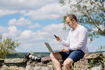 Image showing Handsome businessman with laptop talking on the phone