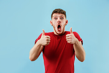 Image showing The happy businessman standing and smiling against blue background.