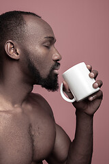 Image showing African man with cup of tea, isolated on pink background