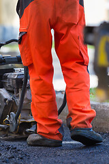 Image showing Construction workers during asphalting road works wearing coveralls. Manual labor on construction site