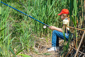 Image showing Girl fishing on a fish sitting in a reed-covered place