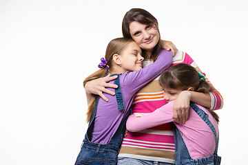 Image showing Children hug their beloved mom, mom happily looks in the frame