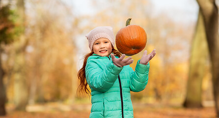 Image showing happy girl playing with pumpkin at autumn park