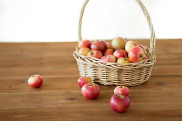 Image showing ripe apples in wicker basket on wooden table