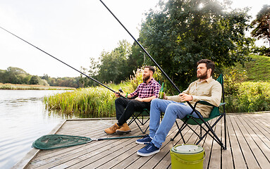 Image showing male friends fishing and drinking beer on lake