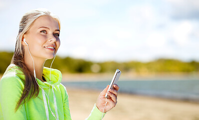 Image showing woman listening to music on smartphone on beach