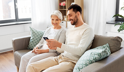 Image showing old mother and adult son with smartphone at home