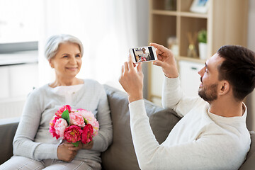 Image showing adult son photographing senior mother at home