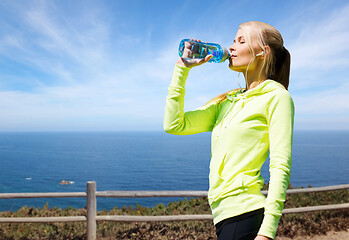 Image showing woman drinking water after exercising at seaside