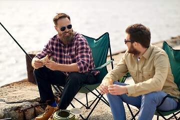 Image showing happy friends fishing and eating sandwiches