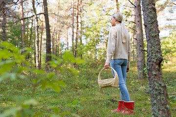 Image showing young woman picking mushrooms in autumn forest