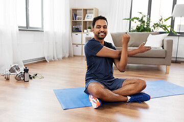 Image showing man training and stretching arm at home