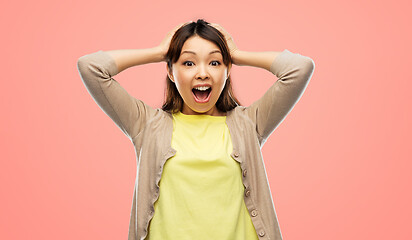 Image showing happy asian woman holding to her head