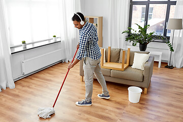 Image showing man in headphones with mop cleaning floor at home