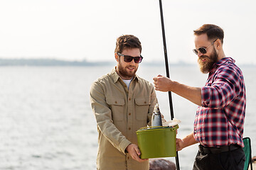 Image showing male friends with fish and fishing rods on pier