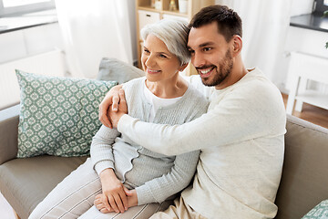 Image showing senior mother with adult son hugging at home